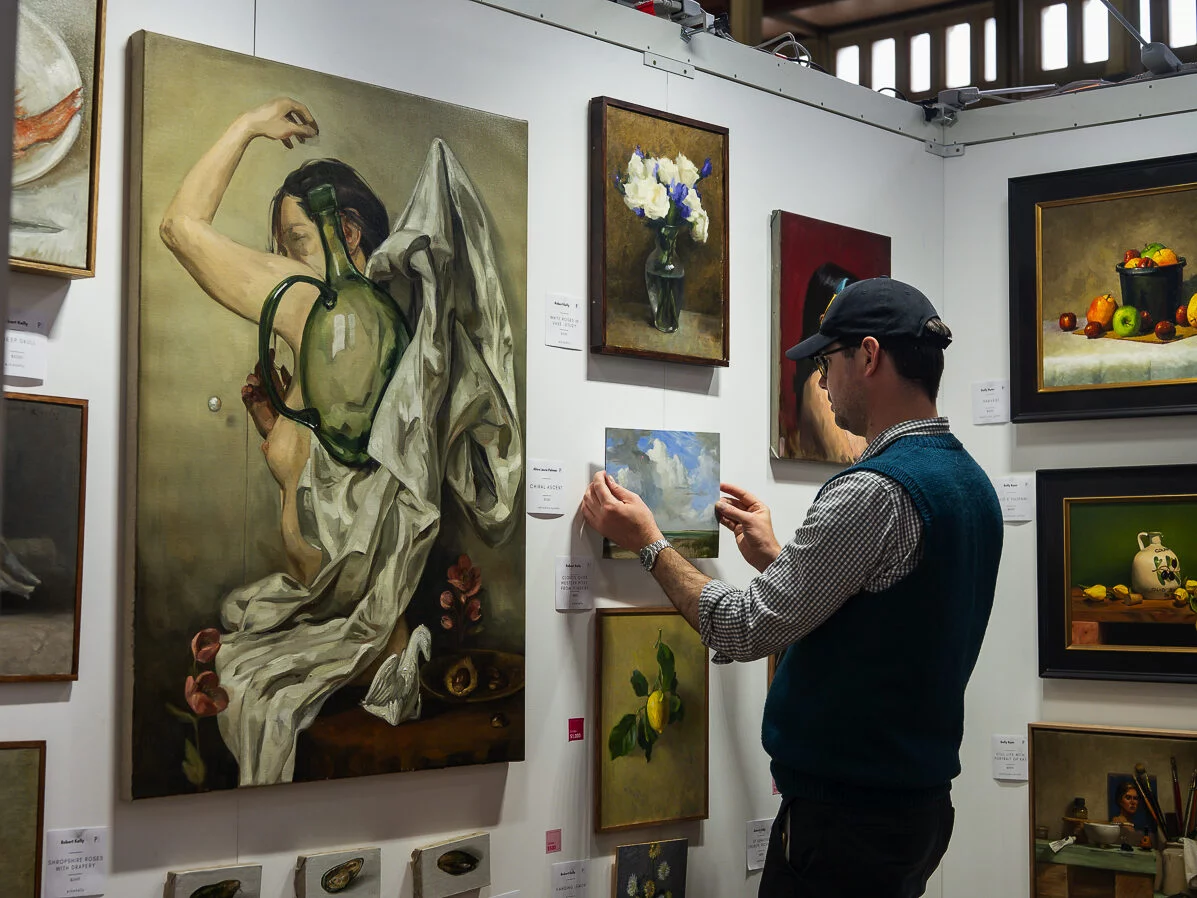 A male gallerist putting artwork on the wall 